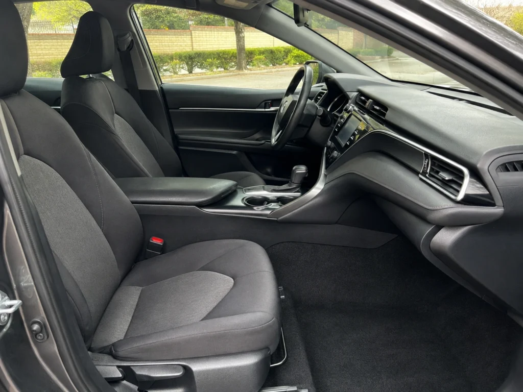 Temporary AI-generated illustration of a 2019 Toyota Camry interior showing the front seats, dashboard and steering wheel. Not a photograph of the actual vehicle for sale.