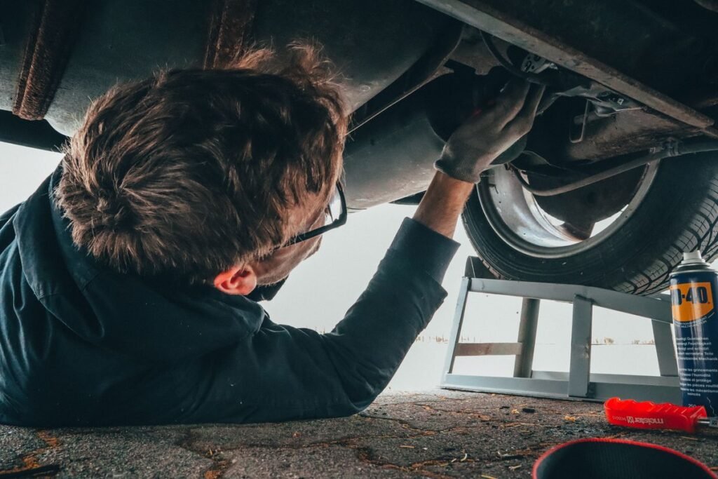 Mechanic leaning over an open hood inspecting the engine bay
